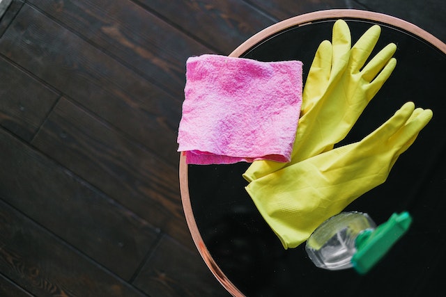 a bucket with rubber gloves and cleaning products in it